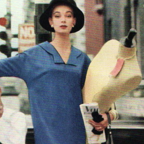 A woman hails a cab while holding a dress form and 1950s Vogue Pattern Book